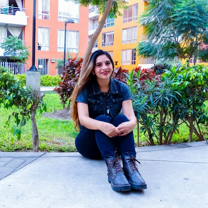 woman sitting on concrete surface near plants during daytime